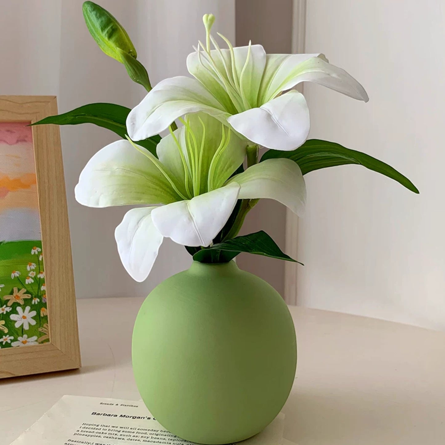 Green ceramic vase with faux lilies styled beside a framed sunset painting — Holm & Hearth