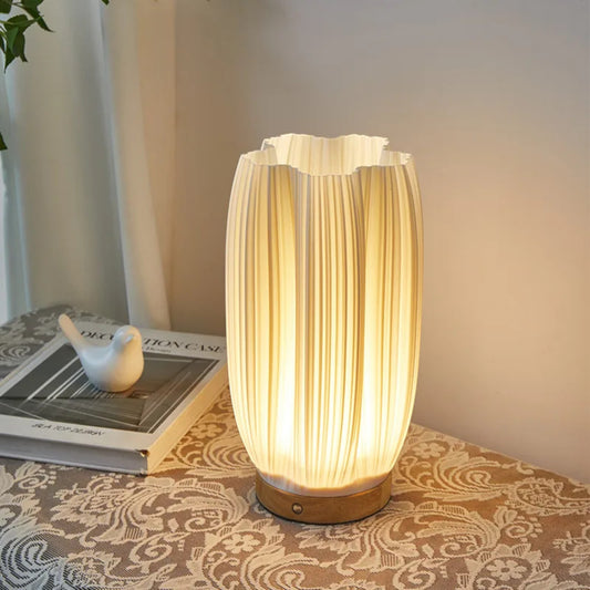 Pleat cordless lamp lit on a bedside table in a cosy bedroom setting — Holm & Hearth