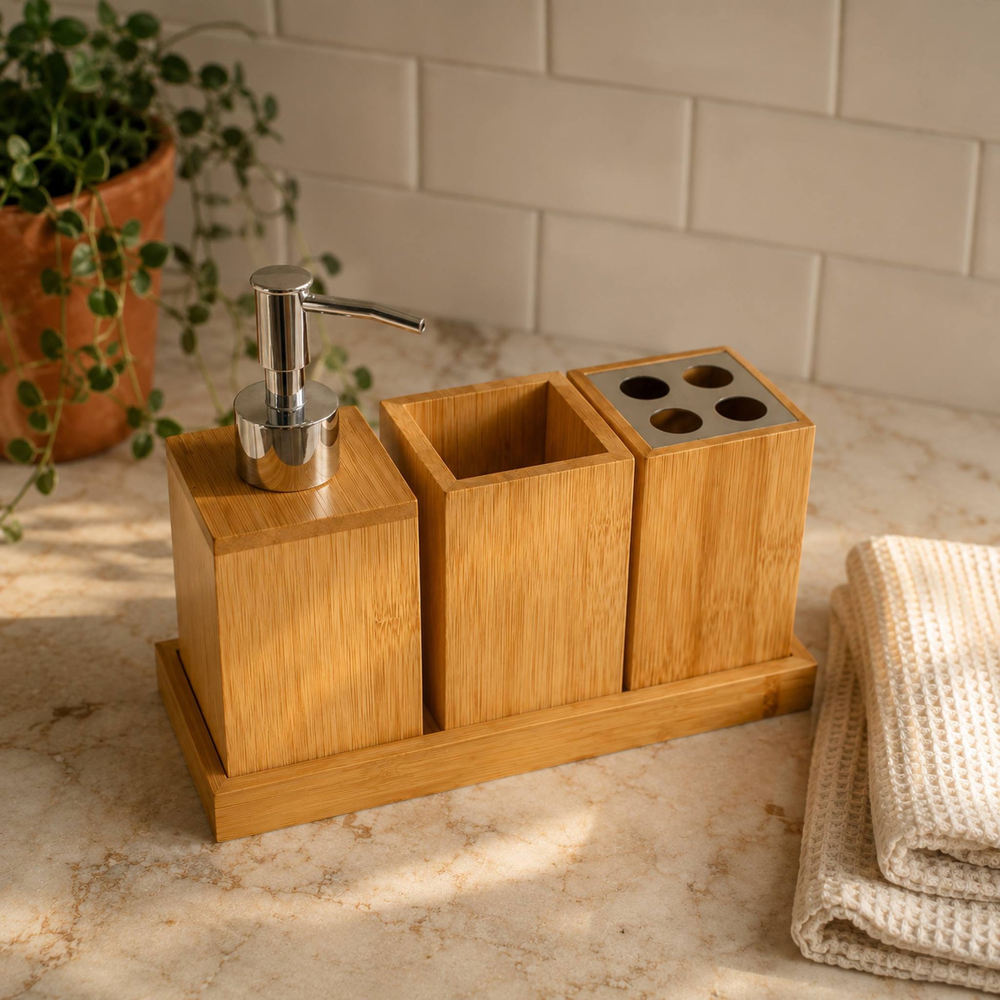 Bamboo bathroom organiser set on cream marble countertop with white subway tile background and folded textured towel, warm bathroom lifestyle