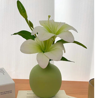 Faux lily in sage-green ceramic vase on a wooden surface with a cream coffee mug — Holm & Hearth