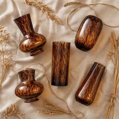 Leopard print glass vase flat lay of all five sculptural amber shapes on honey linen