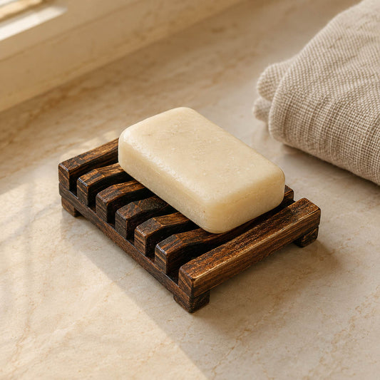 Charred wooden soap rack with natural soap bar on cream marble bathroom counter, warm morning light, hero shot